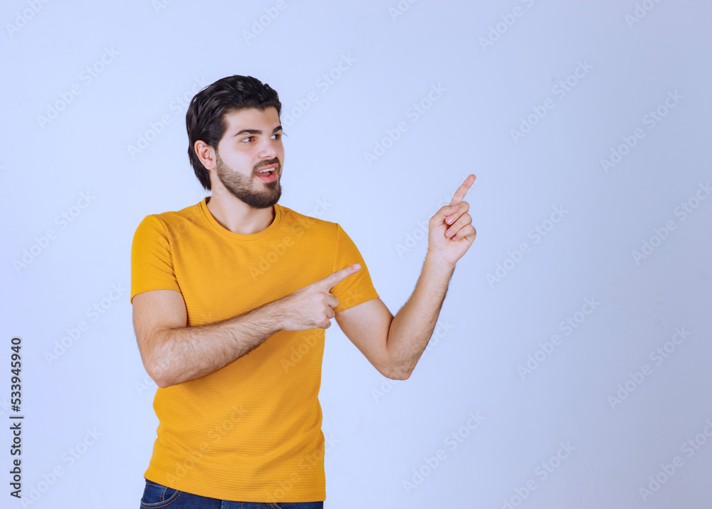 Man in yellow shirt showing something on the right Man in yellow shirt showing something on the right