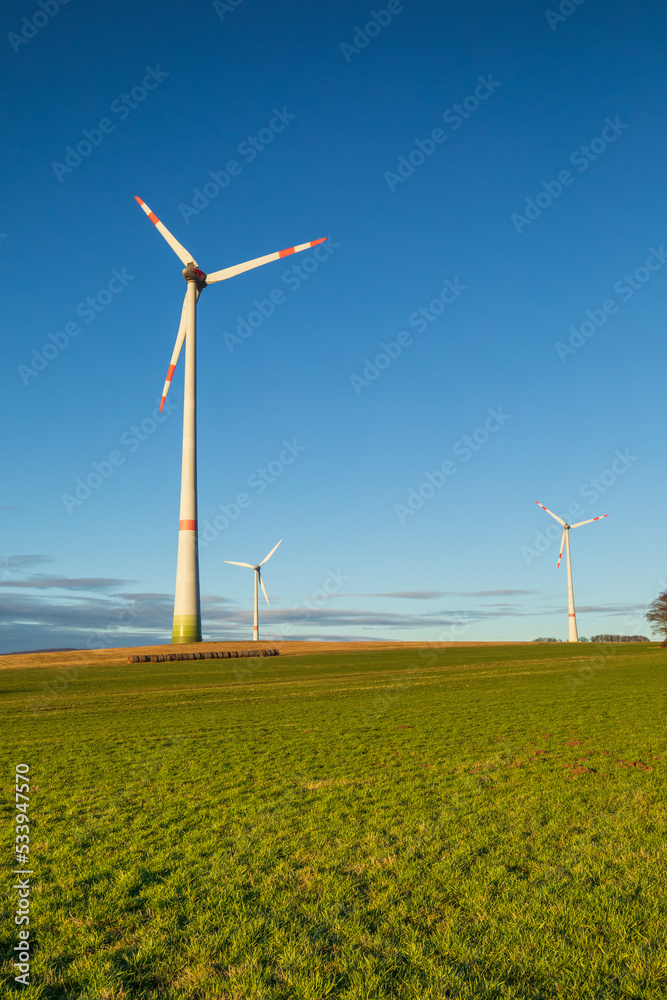 Wind turbines generating clean renewable electricity on a hilltop with a blue sky