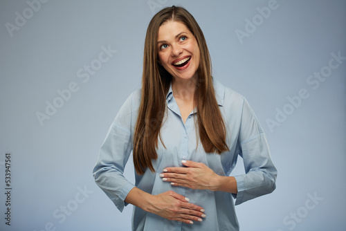 Smiling, happy woman with pleasant feeling in her belly, holding hands on her stomach. isolated portrait.