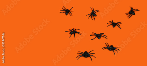 Festive background for Halloween. Black spiders on an orange background. Banner. Copy space. Selective focus.