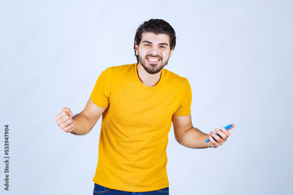 Man in yellow shirt pointing his smartphone and enjoying it Man in yellow shirt pointing his smartphone and enjoying it