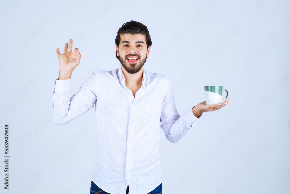 Fototapeta premium Man in a white shirt holding a coffee mug and enjoying it