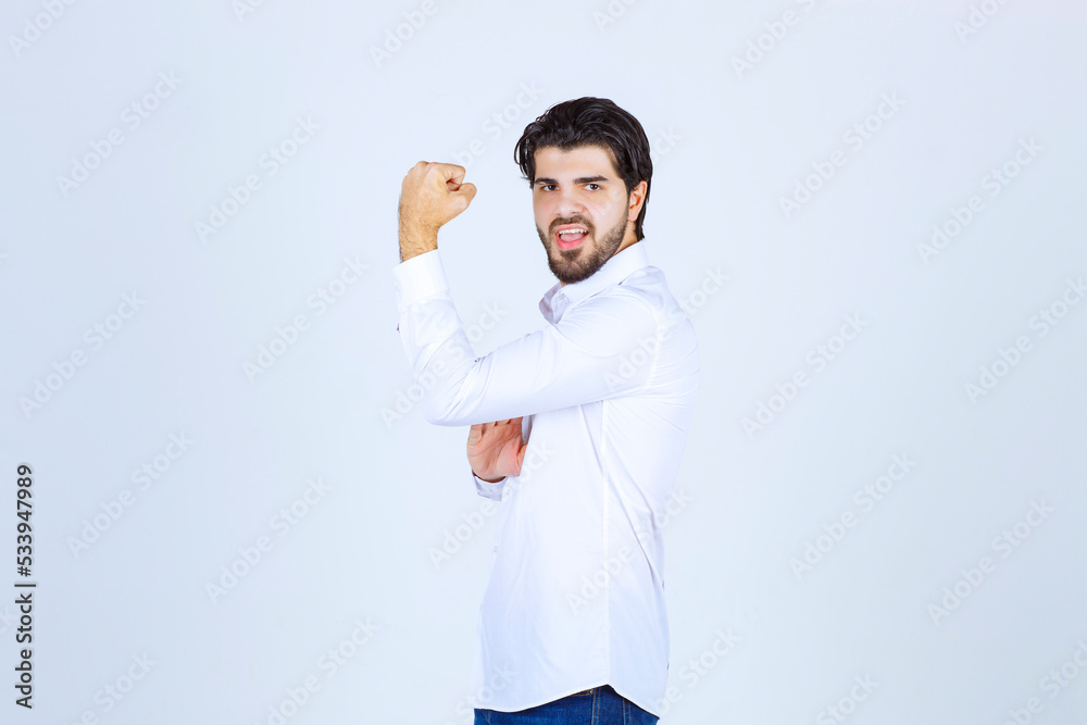 Man in white shirt showing his arm muscles and fist Man in white shirt showing his arm muscles and fist