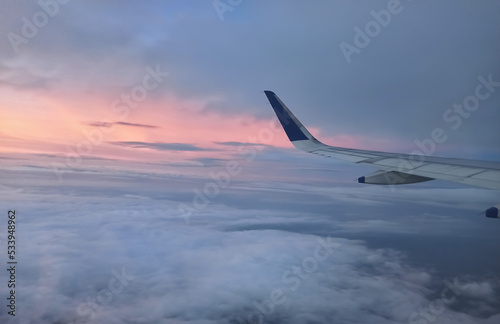 A Scenic View of the Wings of a aero plane flying above the clouds. Travelling by aero plane during sunset.