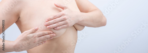 Caucasian woman self checks for breast cancer on white background. Copy space. 