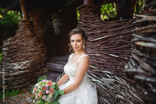 Portrait of the bride. A young girl in a white wedding dress with a bouquet of flowers in her hands on a background of a forest at sunset