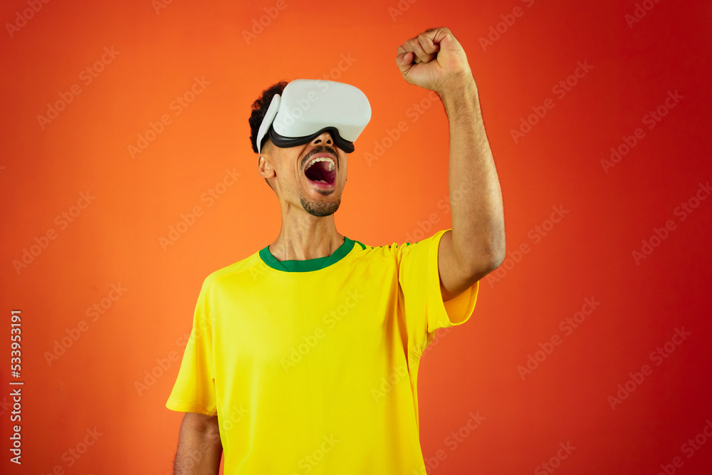 Brazilian Player - Black Man Celebrating With VR Virtual Glasses Isolated on Orange background