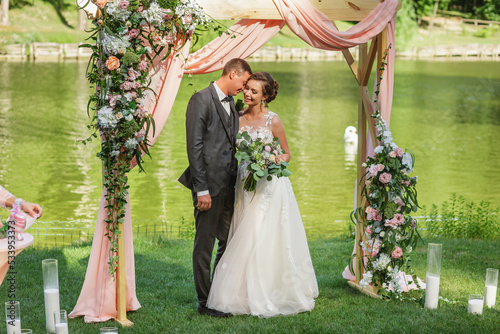 beautiful bride and groom in the wedding ceremony area of live white and pink flowers.
