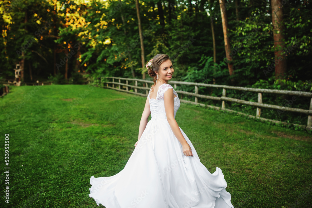 Bride in wedding dress goes on the road in a forest at sunset Bride in wedding dress goes on the road in a forest at sunset
