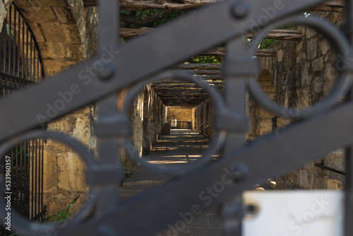 Schilderij op canvas The Alamo side barracks looking through an iron gate