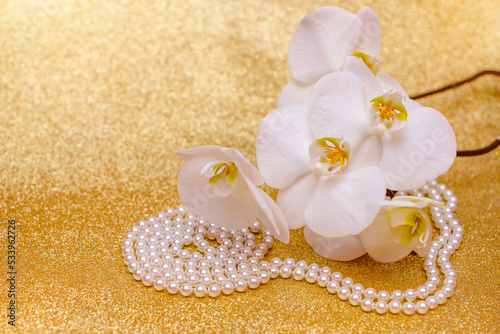 Fototapeta Naklejka Na Ścianę i Meble -  white Orchid and pearl necklace on a shiny gold background
