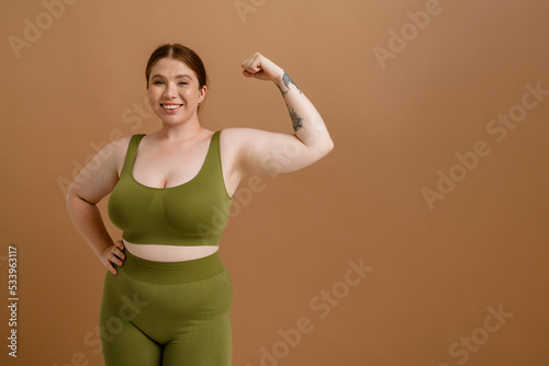 Young beautiful smiling happy plus size girl showing her bicep