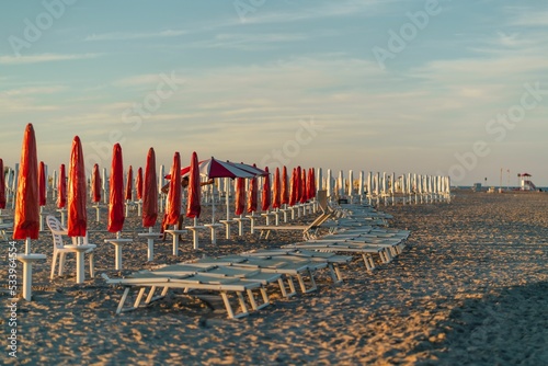 Sunbeds at sunset on the beach of the Adriatic Sea in Lido di Spina, Italy.
