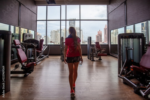 Fitness girl in sportswear in modern gym with skyscrapers view photo