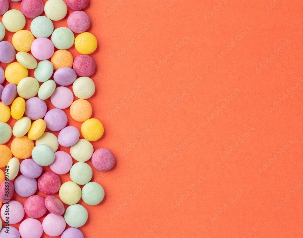 Obraz premium Frame of colorful candies over orange background with copy space