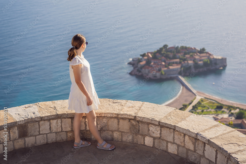 Woman tourist on background of beautiful view of the island of St. Stephen, Sveti Stefan on the Budva Riviera, Budva, Montenegro. Travel to Montenegro concept Portrait of a disgruntled girl sitting at