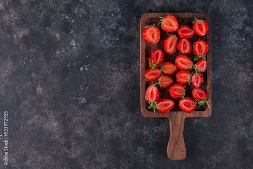 Strawberries on a wooden board on the grey marble, top view