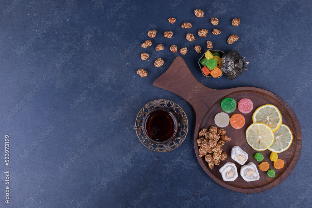 Wooden snack platter with marmelades and a glass of tea in the middle