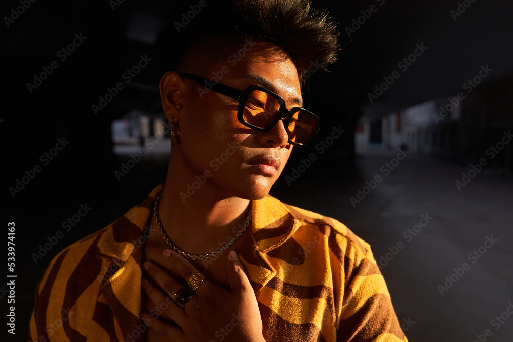 Trendy guy in sunglasses at sunset in city Trendy guy in sunglasses at sunset in city