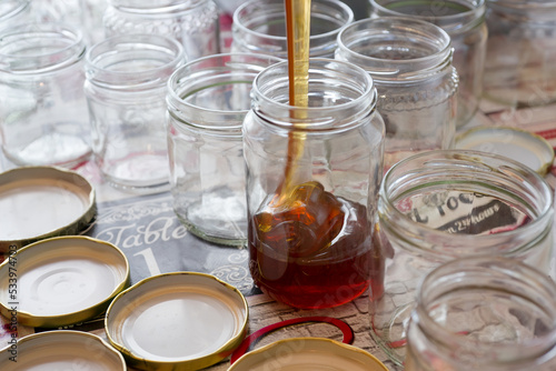 Filling of glass jars of honey on a table
