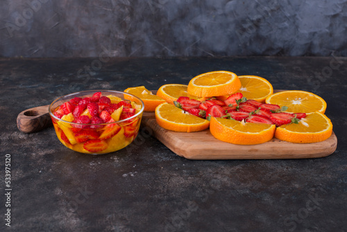 Fruit salad with strawberry and oranges with fruit board aside