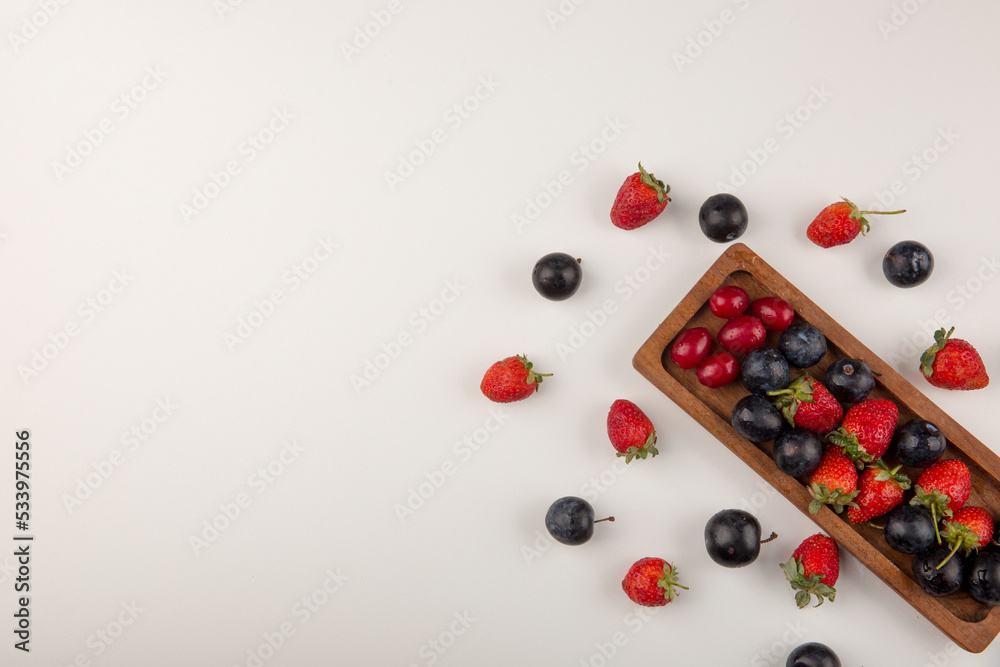 Berry mix on a wooden platter and on the white background