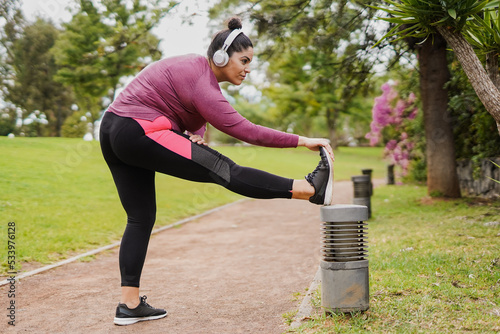 Young curvy woman doing stretching exercise after sport workout routine at city park photo