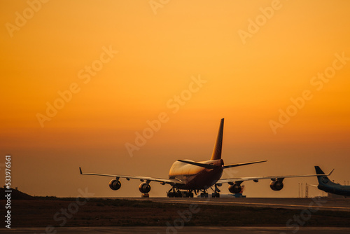 Passenger airplane take off from airport runway against the backdrop of a picturesque evening sky with sun rays