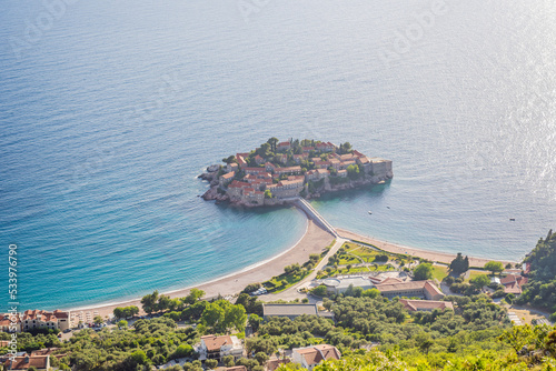 Sveti Stefan island in Budva in a beautiful summer day, Montenegro. Beautiful destinations Portrait of a disgruntled girl sitting at a cafe table