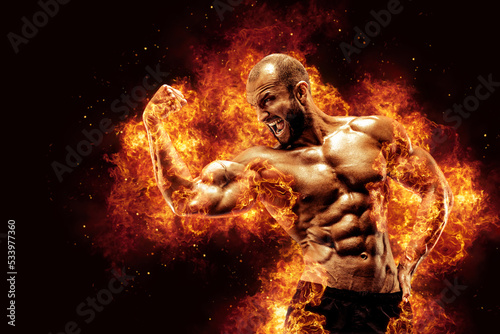 Bodybuilder posing on the fire flames background