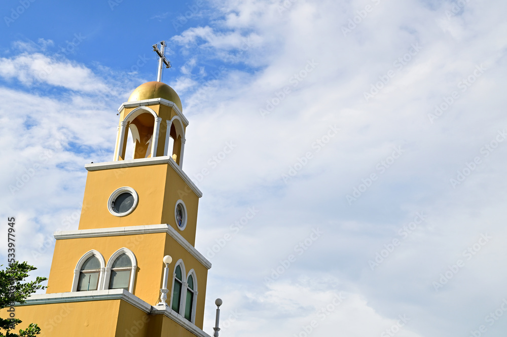 The Golden Church Roof with a cross. Church building roof with holy cross. Cloudy moody blue sky background. Minimal architecture design and detail. Exterior design and detail. 