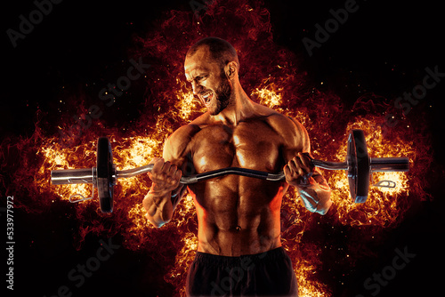 The shirtless abdominal male holds dumbbell. Studio shot in contrasty light © zamuruev