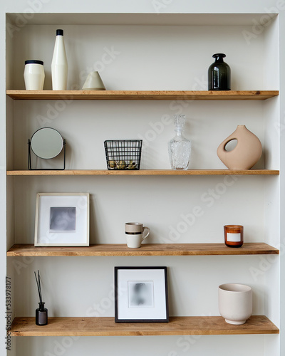 Wooden shelves with beautiful decorative elements, basket, photo frame, mirror, vase photo