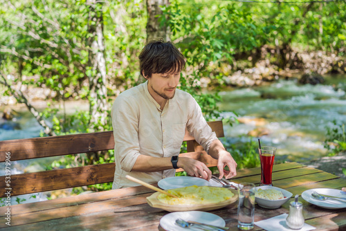 Male tourist eating Traditional Montenegrin Meal. Kacamak in wooden bowl in the outdoor cafe Portrait of a disgruntled girl sitting at a cafe table photo