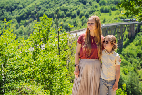 Montenegro. Mom and son tourists in background of Dzhurdzhevich Bridge Over The River Tara. Travel around Montenegro concept. Sights of Montenegro Portrait of a disgruntled girl sitting at a cafe photo