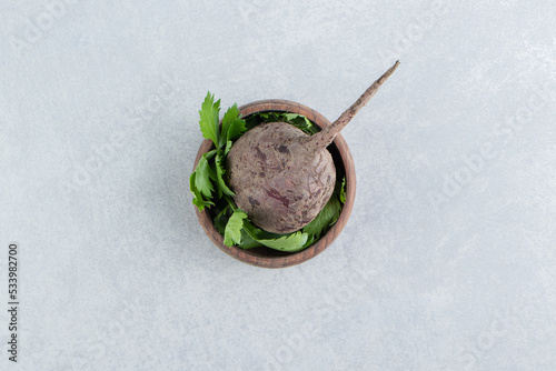 A clay bowl of radish with parsley , on the marble background