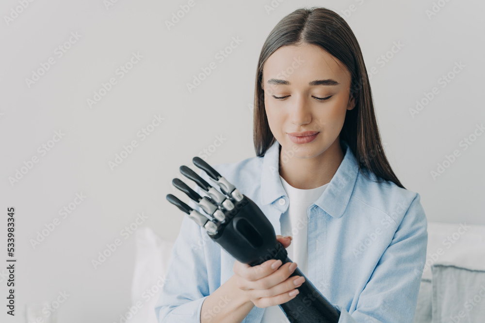 Pretty disabled girl puts together bionic prosthetic arm, adjusting position and grip of prosthesis Pretty disabled girl puts together bionic prosthetic arm, adjusting position and grip of prosthesis