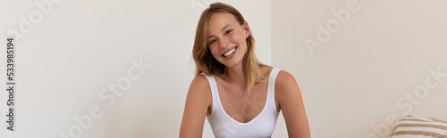 Positive blonde woman looking at camera at home, banner.