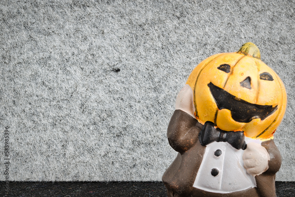 halloween figurine with tuxedo and a pumpkin instead of head. grey and black background.