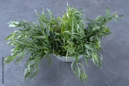 Newly harvested tarragon in a bowl, on the marble background photo