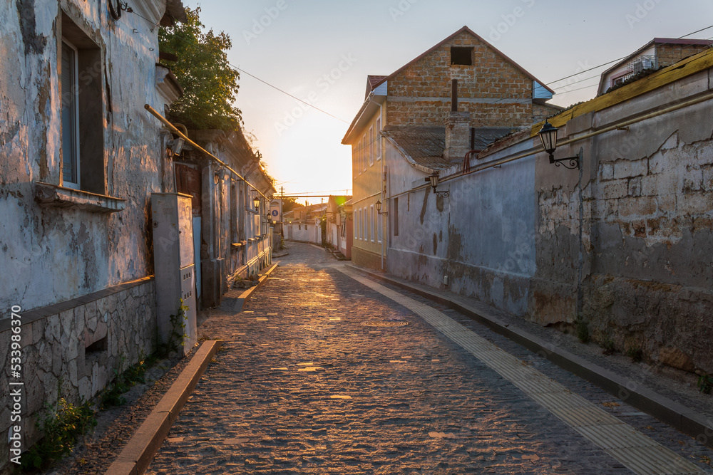 Street of the Old Town of Evpatoria at sunset. Narrow streets with stone pavements of the old resort town.
