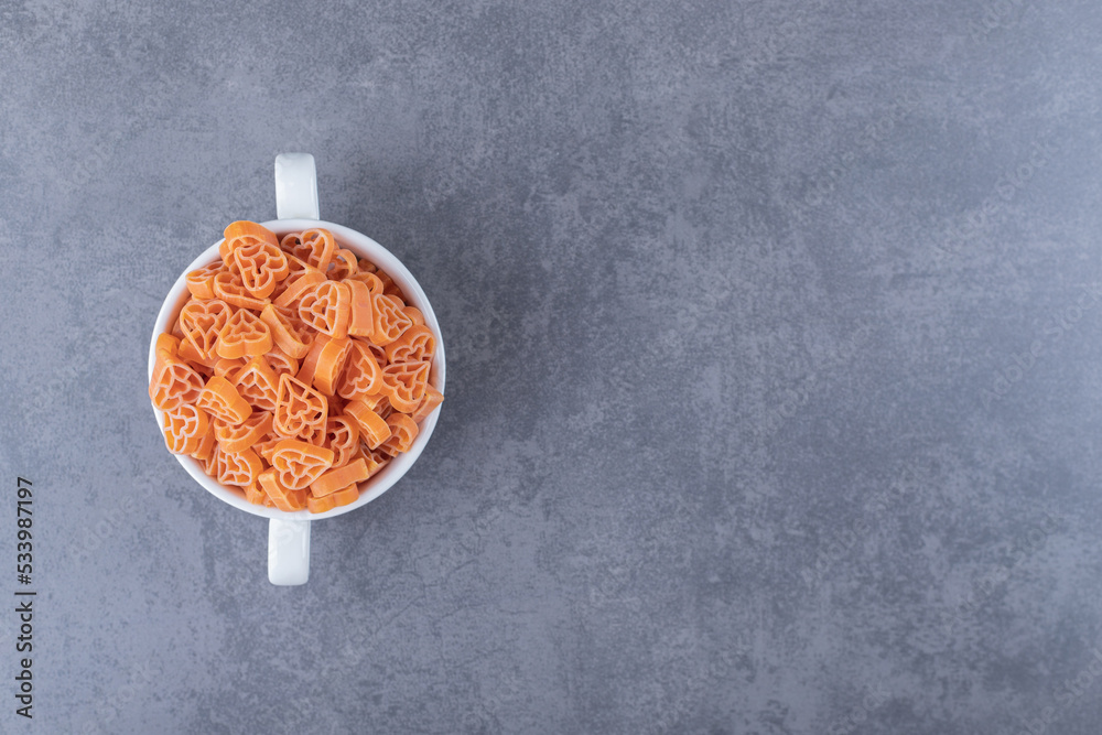 Fototapeta premium Pile of raw heart-shaped pasta in mug