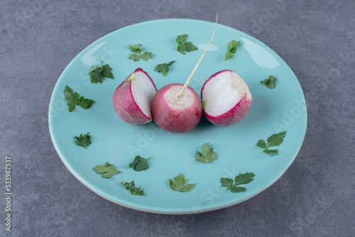 Radish and greenery on the plate , on the marble background