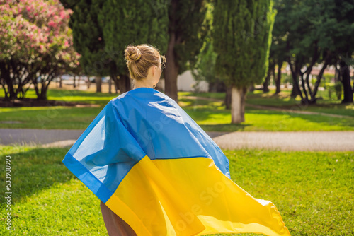 A woman put a Ukrainian flag on his shoulders. concept Ukrainian patriot  rally in support of Ukraine Portrait of a disgruntled girl sitting at a cafe table