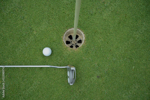 Golf ball and golf club on green in the evening golf course with sunshine in thailand