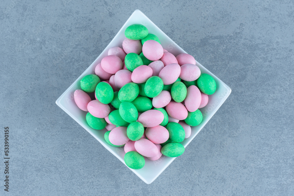 Small colorful chocolate in the bowl, on the marble background