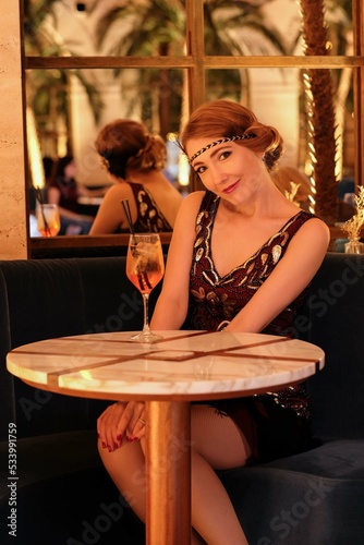 Woman in 1920 style clothes with a glass. Beautiful girl retro flapper style retro vintage roaring 20s. 