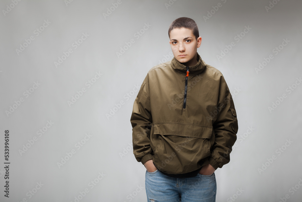 Girl with short hair wearing jacket and jeans against gray background. . Girl with short hair wearing jacket and jeans against gray background. .