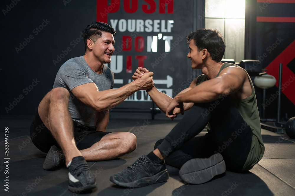 Naklejka premium Muscular man athlete in sportswear relaxing and handshake with friend after exercises at fitness gym. Workout for good health concept.