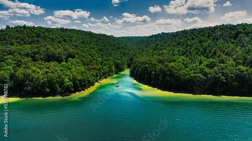 Aerial view of lush rainforests on a river shore under a cloudy sky